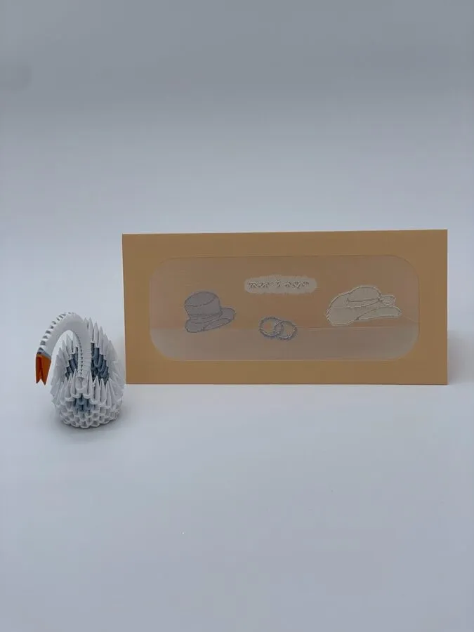 Mini cygne en origami posé à côté d'une carte