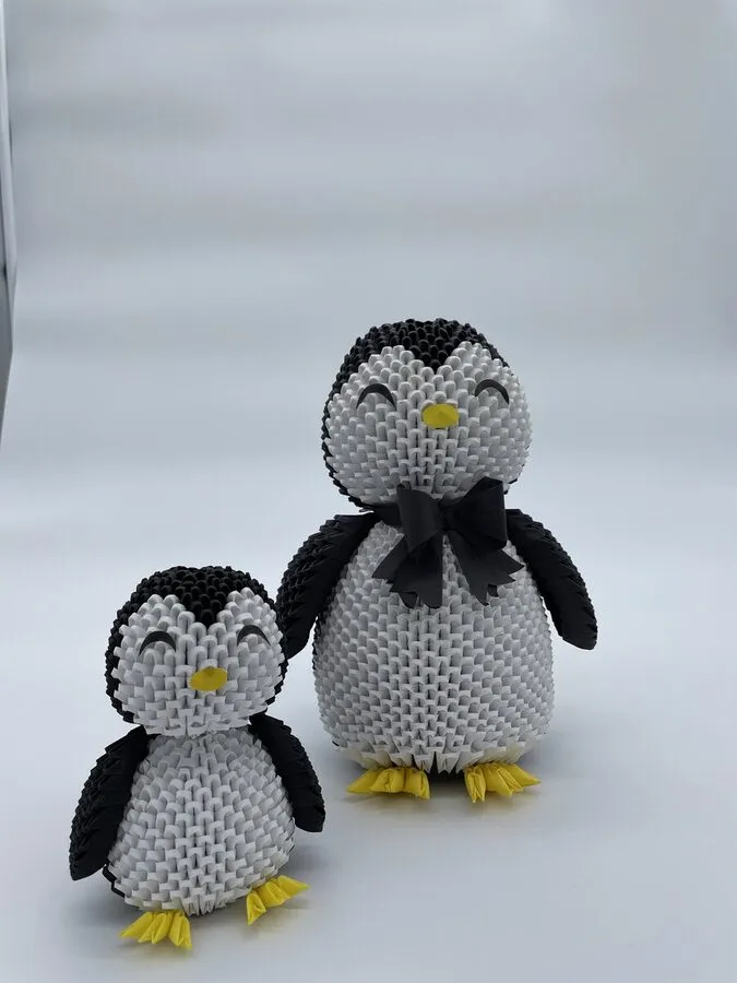 Grand pingouin en origami avec nœud papillon noir, accompagné du petit pingouin